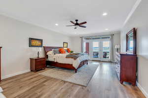 Bedroom with access to outside, light wood finished floors, baseboards, and ornamental molding