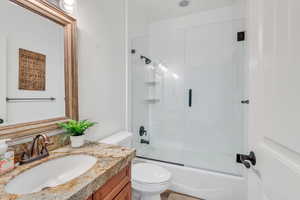 Bathroom with enclosed tub / shower combo, vanity, and toilet