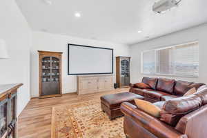 Home theater featuring light wood-style floors, baseboards, and recessed lighting
