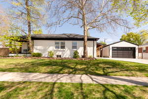 Single story home featuring a garage, a front lawn, concrete driveway, and stucco siding