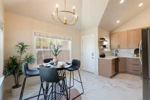 Kitchen with light brown cabinetry, freestanding refrigerator, lofted ceiling, dishwashing machine, and open shelves