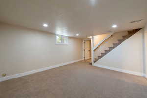 Below grade area featuring baseboards, visible vents, recessed lighting, and stairs