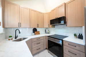 Kitchen with stainless steel electric range, light brown cabinetry, black microwave, and a sink