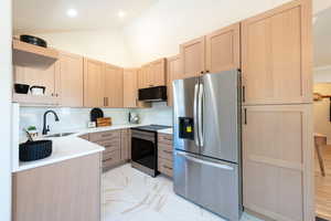 Kitchen with marble finish floor, stainless steel appliances, open shelves, light brown cabinets, and a sink