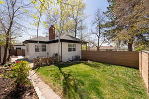 Exterior space featuring central AC, a chimney, a fenced backyard, a yard, and stucco siding