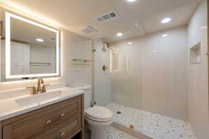 Full bath featuring visible vents, toilet, vanity, and a walk in shower