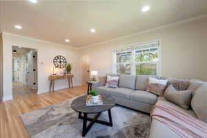 Living area featuring light wood-style floors, arched walkways, and recessed lighting