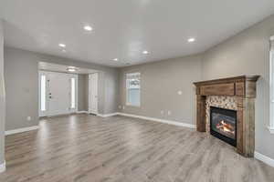 Unfurnished living room featuring recessed lighting, baseboards, light wood finished floors, and a tile fireplace