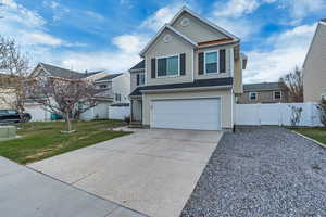 Traditional-style home featuring a front yard, fence, a garage, and concrete driveway