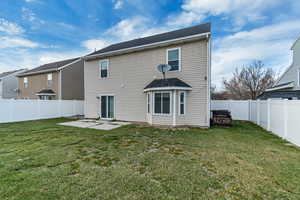 Back of property featuring a yard, a fenced backyard, and a patio area