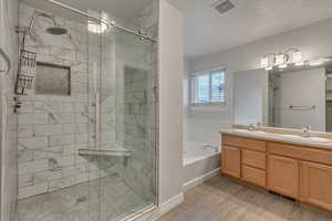 Full bathroom with a shower stall, a bath, visible vents, and a sink