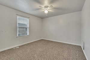 Empty room featuring visible vents, baseboards, a ceiling fan, and carpet flooring