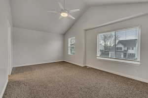 Carpeted empty room with ceiling fan, baseboards, and lofted ceiling