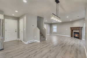Unfurnished living room featuring visible vents, baseboards, stairway, and light wood finished floors