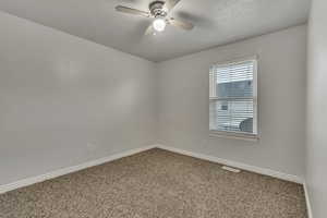 Carpeted spare room featuring ceiling fan, baseboards, and visible vents