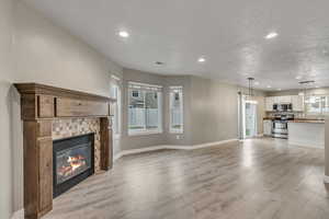 Unfurnished living room featuring light wood-style flooring, recessed lighting, a tile fireplace, and a textured ceiling