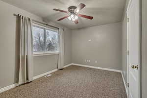 Carpeted empty room featuring a textured ceiling, baseboards, a ceiling fan, and visible vents