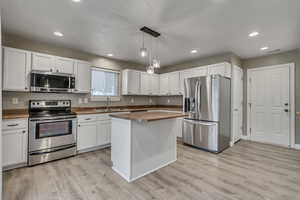 Kitchen with a sink, light wood-style flooring, appliances with stainless steel finishes, and white cabinetry