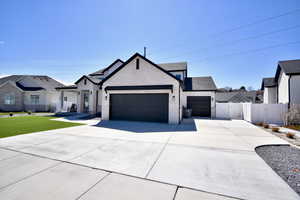 Modern farmhouse with an attached garage, fence, concrete driveway, brick siding, and a gate