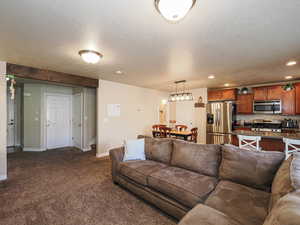 Living area featuring recessed lighting, baseboards, dark carpet, and a textured ceiling