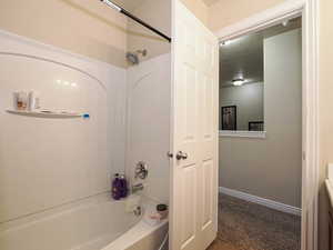 Bathroom with bathing tub / shower combination, a textured ceiling, vanity, and baseboards