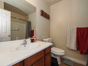 Bathroom with toilet, curtained shower, and vanity