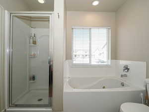 Bathroom featuring a bath, toilet, recessed lighting, and a stall shower