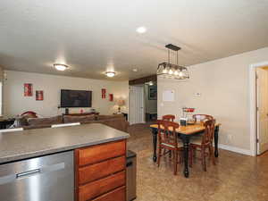 Kitchen featuring open floor plan, dishwasher, a textured ceiling, and dark countertops