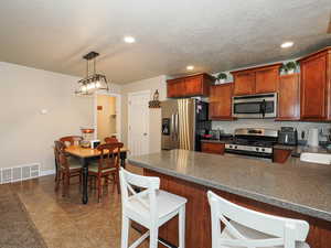 Kitchen featuring dark countertops, visible vents, appliances with stainless steel finishes, and a peninsula