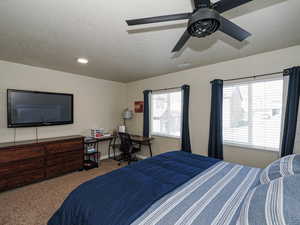 Bedroom featuring baseboards, carpet flooring, a textured ceiling, a ceiling fan, and visible vents