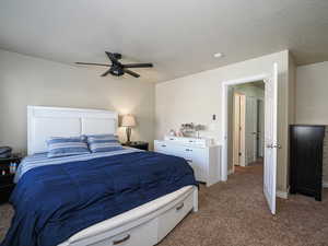 Bedroom with a textured ceiling, light colored carpet, baseboards, and a ceiling fan