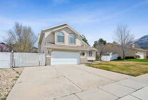 Traditional-style home with stucco siding, a front yard, fence, an attached garage, and driveway