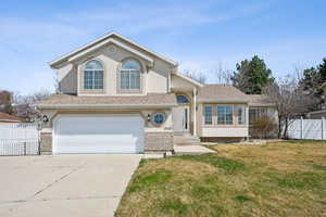 View of front of home with concrete driveway, a garage, fence, and stucco siding