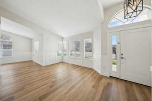 Foyer with wood finished floors and a wainscoted wall