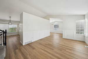 Bonus room featuring visible vents, light wood-type flooring, an inviting chandelier, and a healthy amount of sunlight
