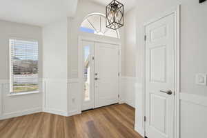 Foyer featuring an inviting chandelier, wainscoting, and wood finished floors