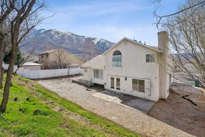 Rear view of house featuring stucco siding, a chimney, fence, french doors, and a mountain view