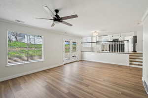 Unfurnished living room featuring visible vents, baseboards, ornamental molding, a ceiling fan, and light wood-style flooring