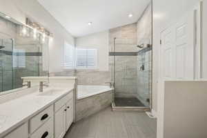 Bathroom with a shower stall, a bath, vanity, and lofted ceiling