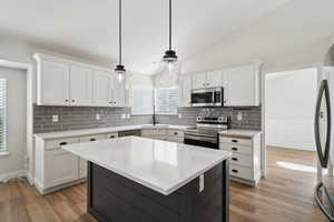 Kitchen featuring a sink, white cabinets, appliances with stainless steel finishes, and light wood finished floors