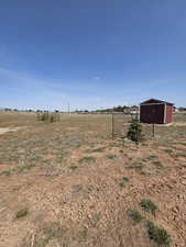 View of yard with an outbuilding, a pole building, fence, and a rural view