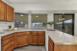 Kitchen featuring brown cabinets, light countertops, a sink, and a peninsula
