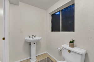 Half bath with tile patterned floors, baseboards, and toilet