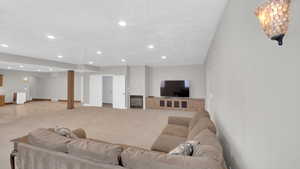 Living area with light carpet, recessed lighting, and baseboards