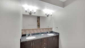 Bathroom with double vanity, a sink, and decorative backsplash