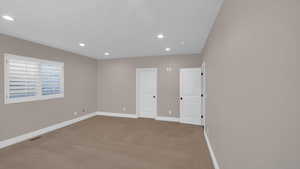 Carpeted spare room featuring visible vents, baseboards, and recessed lighting