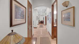 Corridor featuring recessed lighting, arched walkways, stone finish floor, and baseboards