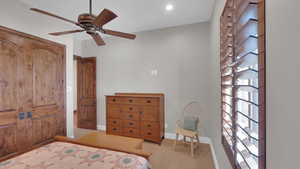 Unfurnished bedroom with light colored carpet, baseboards, and a ceiling fan