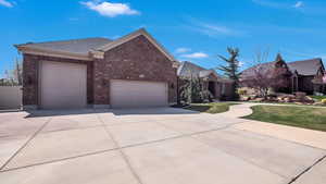 View of front facade featuring a garage, concrete driveway, a front lawn, and brick siding