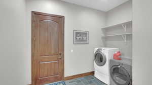 Laundry room with baseboards, laundry area, washing machine and clothes dryer, and stone finish flooring